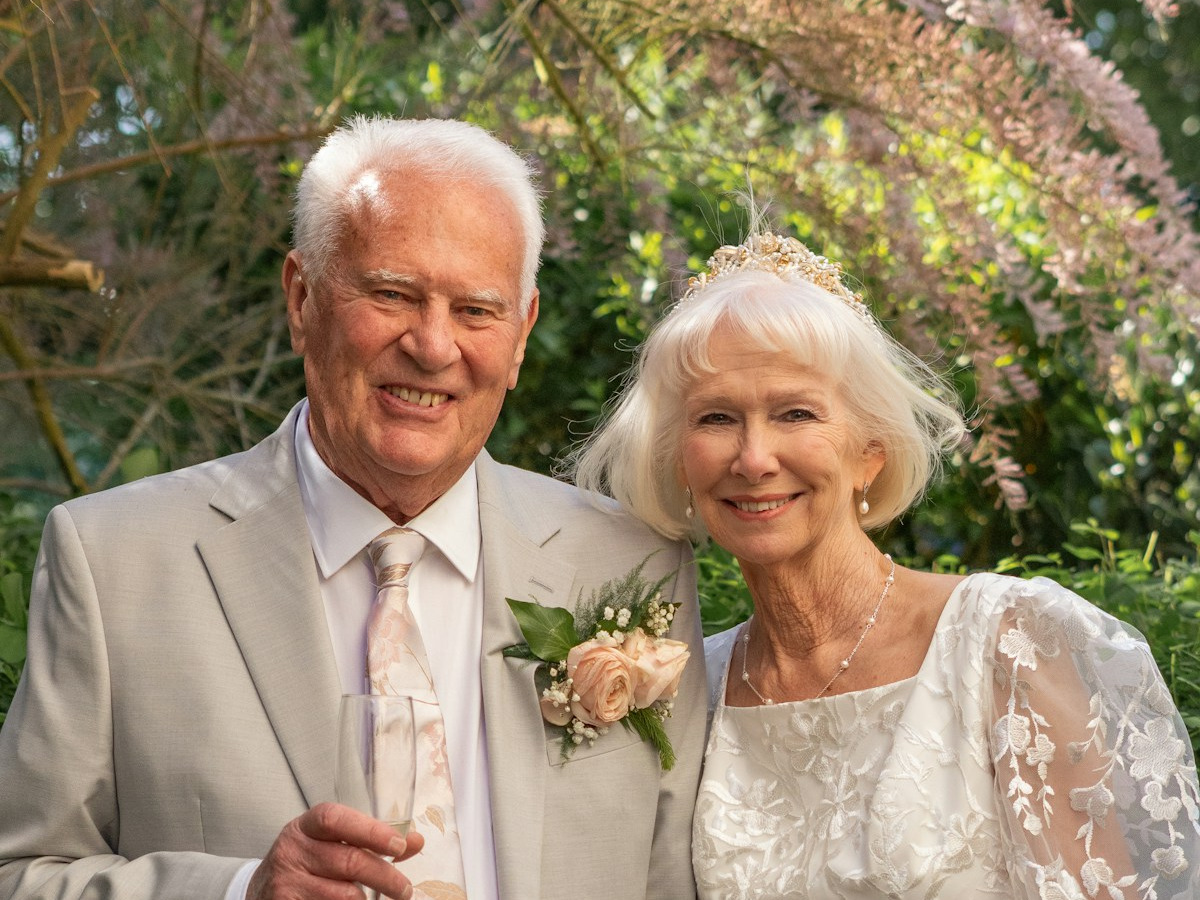 An older couple smiling together in wedding attire, both faces clearly visible